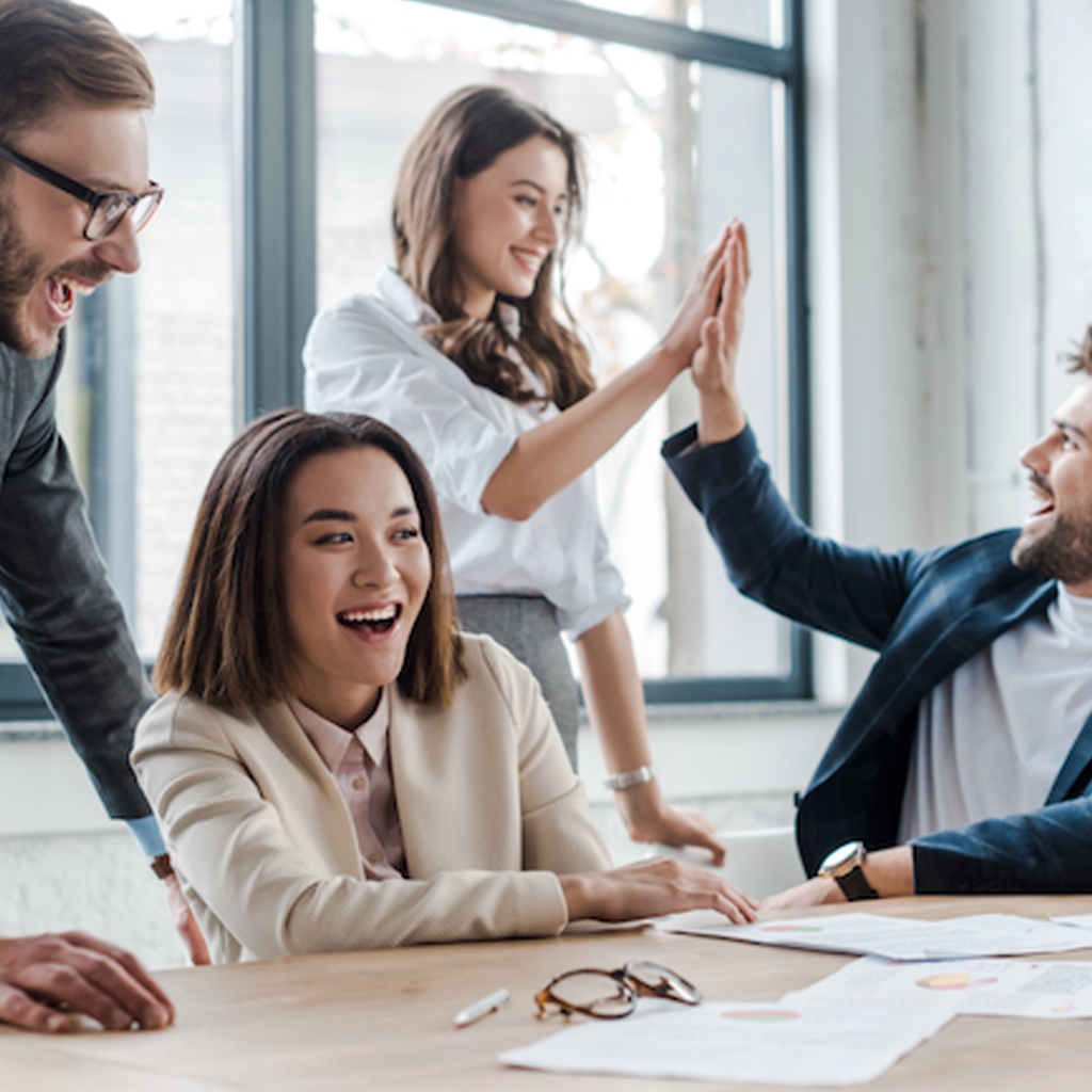 Four tech senior managaers super happy and congratulating each other over their HR project for AI training in a bright, super modern office workspace
