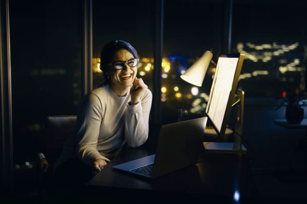 Workforce training on AI, 2 smiling women junior managers in a modern office tower doing AI testing, a modern skyline at dusk can be seen through the window